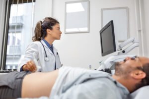 Médica gastroenteróloga realizando diagnóstico abdominal con ecógrafo a paciente recostado, evaluación digestiva en centro médico de Cartagena