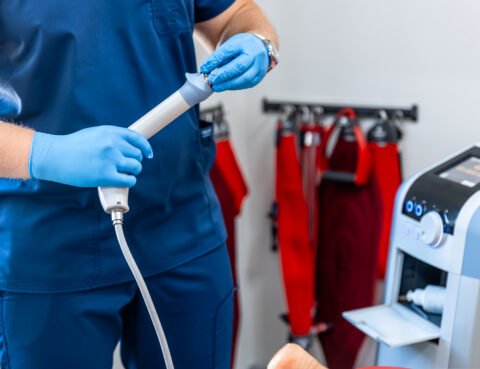 Médico gastroenterólogo con guantes quirúrgicos sosteniendo equipo de endoscopia digestiva junto a máquina especializada en clínica de Cartagena