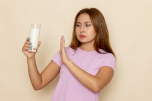 Mujer joven rechazando un vaso de leche con gesto de malestar, representando la intolerancia a la lactosa y sus síntomas digestivos