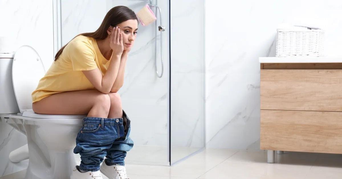 Mujer preocupada en un baño al experimentar molestias digestivas